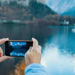 En selfie bild där en person tar foto av en vacker sjö och berg med sin mobil.