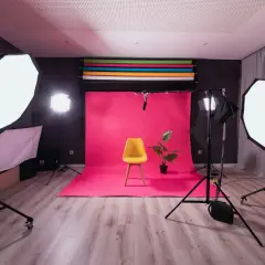 Fotostudio med rosa bakgrund, gul stol och en växt. Flera softboxar ger en jämn belysning, medan en bakgrundsbelysning skapar en fin **rim light** runt motivet.