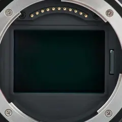 Kamerans sensor med en mörk, reflekterande yta. Runt sensorn syns objektivfattningen och kontakter. En liten vertikal lucka antyder en mekanism, kanske en del av den **rolling shutter**-funktionen.