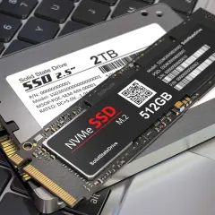 Två SSD-enheter, en 2,5-tums och en M.2 NVMe, ligger på ett laptop-tangentbord. Perfekt för att installera SSD och uppgradera din dator.