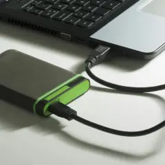 Extern hårddisk med grön kant ansluten till en bärbar dator via usb 3.2.