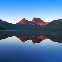 Bergstoppar i solnedgången speglas i en lugn sjö. En vacker vy som en samling av reels med bilder.