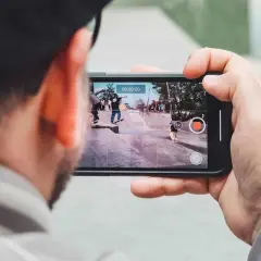 Person filma med mobilen en skateboardpark där flera åker skateboard.