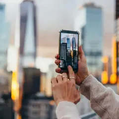 En person håller upp en mobiltelefon för att skanna bild av skyskrapor i New York.