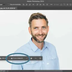 Man använder Photoshop för att ta bort bakgrunden på en bild av en leende man.