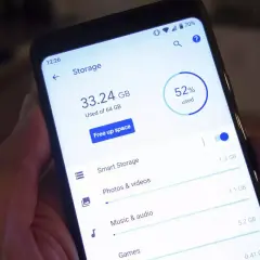 En hand håller en telefon som visar lagringsutrymme. 33.24 GB av 64 GB används, 52% totalt.