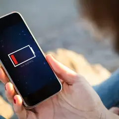 En person håller en mobil med lågt batteri. Dags att uppdatera telefonen och hitta en laddare!