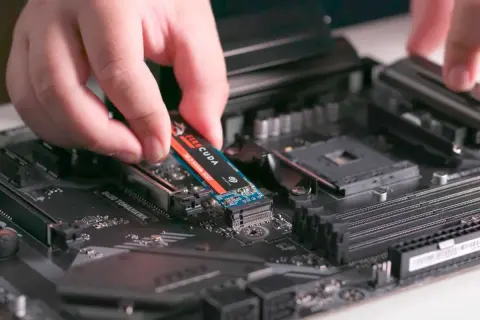 En hand monterar en M.2 NVMe SSD på ett moderkort. Detta är en snabb lagringslösning som kan förbättra datorns prestanda avsevärt.