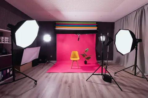 Fotostudio med rosa bakgrund, gul stol och en växt. Flera softboxar ger en jämn belysning, medan en bakgrundsbelysning skapar en fin **rim light** runt motivet.