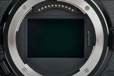 Kamerans sensor med en mörk, reflekterande yta. Runt sensorn syns objektivfattningen och kontakter. En liten vertikal lucka antyder en mekanism, kanske en del av den **rolling shutter**-funktionen.
