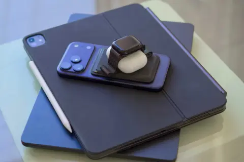 En stapel Apple-produkter: en iPad med tangentbord, en iPhone, en Apple Watch och AirPods. Perfekt för att skapa egna flera bakgrundsbilder iPhone.