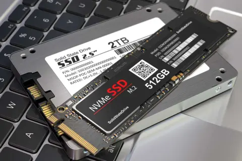 Två SSD-enheter, en 2,5-tums och en M.2 NVMe, ligger på ett laptop-tangentbord. Perfekt för att installera SSD och uppgradera din dator.
