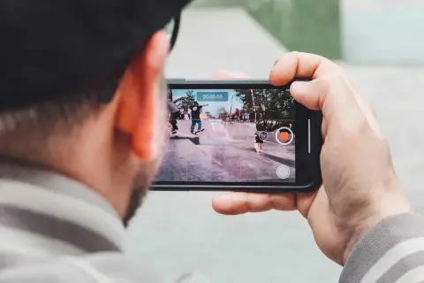 Person filma med mobilen en skateboardpark där flera åker skateboard.