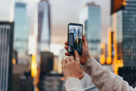 En person håller upp en mobiltelefon för att skanna bild av skyskrapor i New York.
