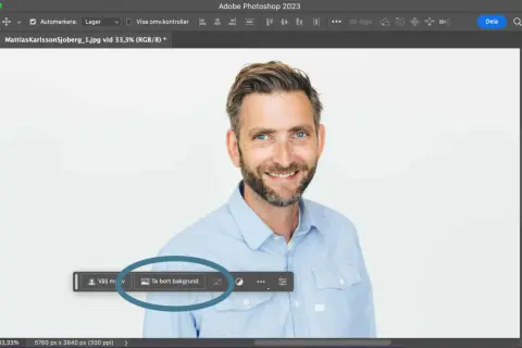 Man använder Photoshop för att ta bort bakgrunden på en bild av en leende man.
