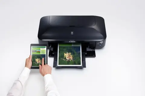 En person använder en surfplatta för att skriva ut en bild av ett slott på en Canon Pixma IX6850.