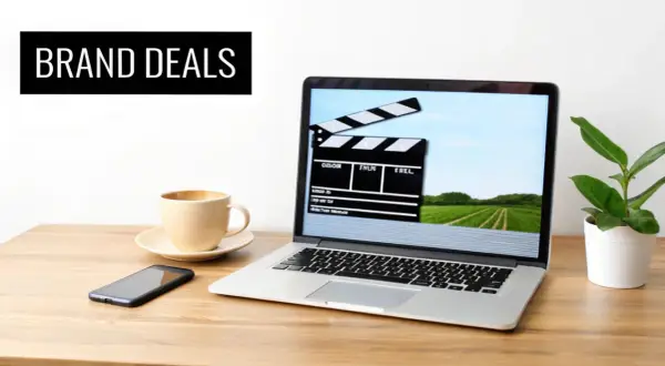 Laptop med filmklippstavla på skärmen, kaffe, mobil och en planta. Perfekt för att skapa insta reels med brand deals.