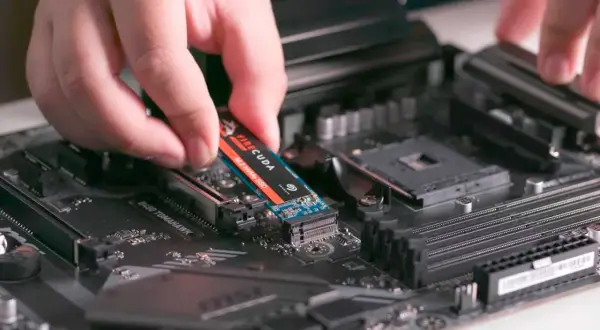 En hand monterar en M.2 NVMe SSD på ett moderkort. Detta är en snabb lagringslösning som kan förbättra datorns prestanda avsevärt.