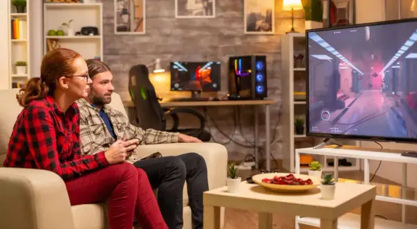 Ett par spelar tv-spel på en stor skärm, en bekväm casta från dator till tv-upplevelse.