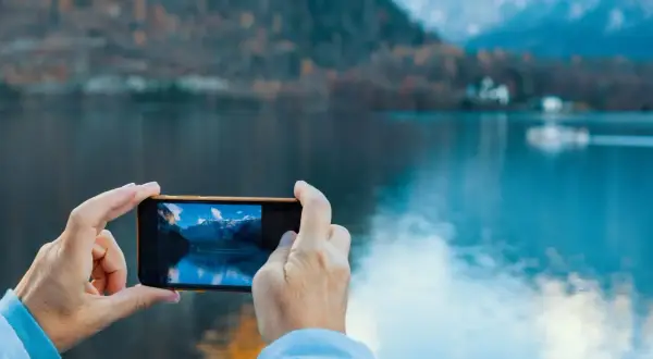 En selfie bild där en person tar foto av en vacker sjö och berg med sin mobil.