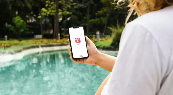 En person håller upp en mobil med Instagram Reels-ikonen. Vad betyder reels? Korta videoklipp som delas på sociala medier.