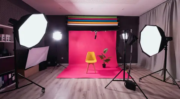 Fotostudio med rosa bakgrund, gul stol och en växt. Flera softboxar ger en jämn belysning, medan en bakgrundsbelysning skapar en fin **rim light** runt motivet.