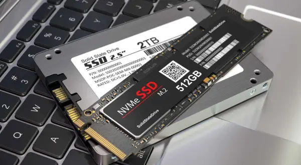 Två SSD-enheter, en 2,5-tums och en M.2 NVMe, ligger på ett laptop-tangentbord. Perfekt för att installera SSD och uppgradera din dator.