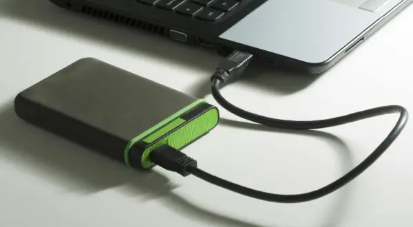 Extern hårddisk med grön kant ansluten till en bärbar dator via usb 3.2.
