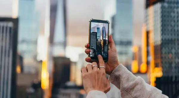 En person håller upp en mobiltelefon för att skanna bild av skyskrapor i New York.