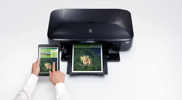 En person använder en surfplatta för att skriva ut en bild av ett slott på en Canon Pixma IX6850.
