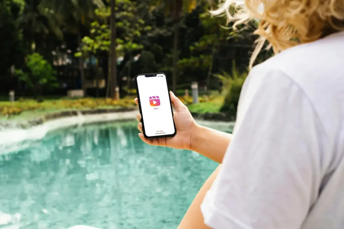 En person håller upp en mobil med Instagram Reels-ikonen. Vad betyder reels? Korta videoklipp som delas på sociala medier.