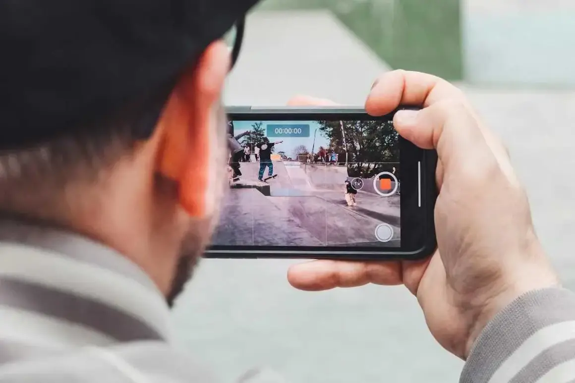 Person filma med mobilen en skateboardpark där flera åker skateboard.