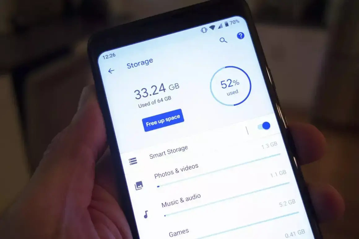 En hand håller en telefon som visar lagringsutrymme. 33.24 GB av 64 GB används, 52% totalt.