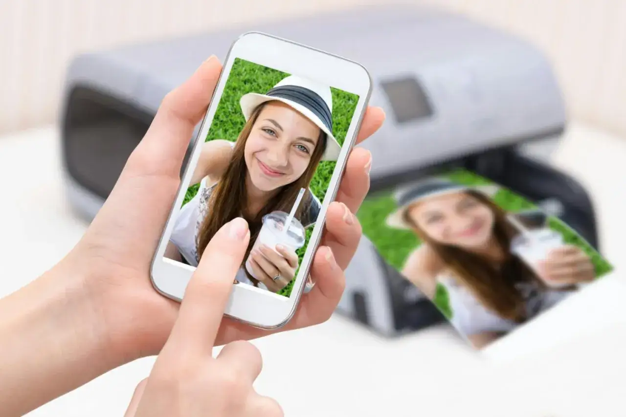 En person h&aring;ller en mobiltelefon med en bild p&aring; en leende tjej med hatt. Bredvid syns en utskrift av samma bild fr&aring;n en skrivare. Enkelt att skriva ut fr&aring;n mobilen!