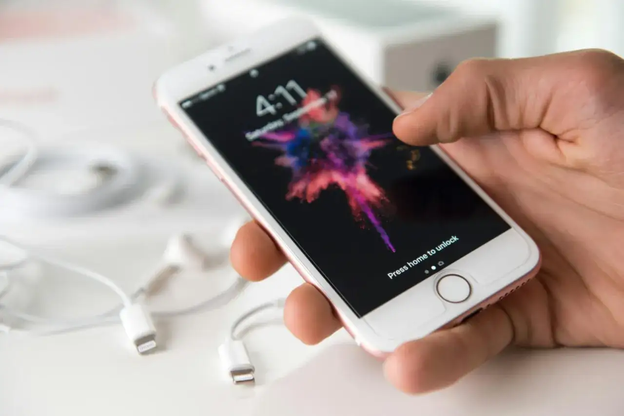En hand h&aring;ller en iPhone med en f&auml;rgstark bakgrundsbild. Kanske &auml;r det dags att byta fr&aring;n Android till iPhone?