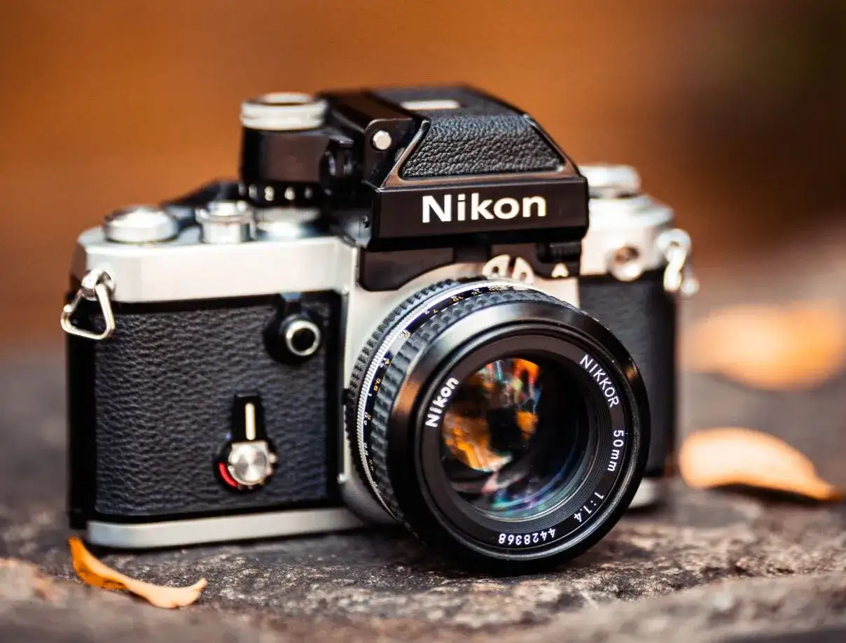 En klassisk Nikon spegelreflexkamera, perfekt för att skapa tidlösa analoga bilder. Linsen reflekterar en färgsprakande värld.