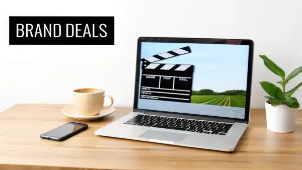 Laptop med filmklippstavla på skärmen, kaffe, mobil och en planta. Perfekt för att skapa insta reels med brand deals.