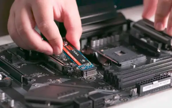 En hand monterar en M.2 NVMe SSD på ett moderkort. Detta är en snabb lagringslösning som kan förbättra datorns prestanda avsevärt.