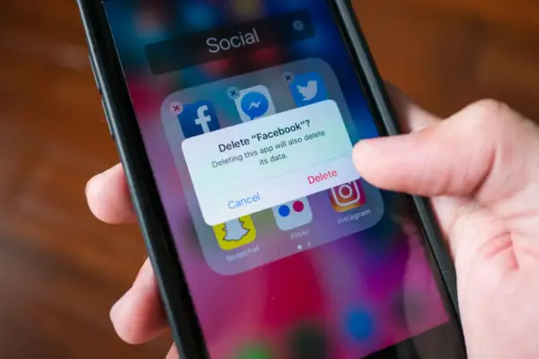 En person trycker på "Delete" för att ta bort appar från sin telefon.