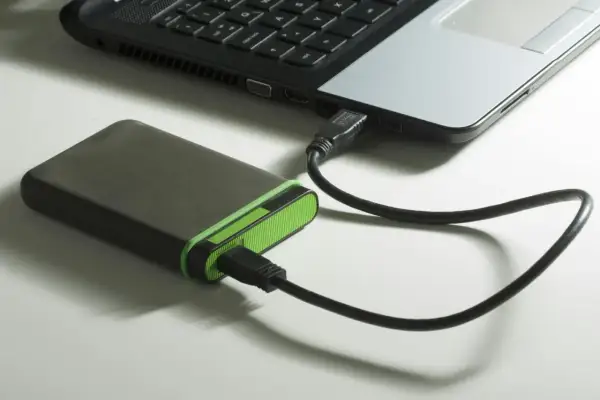 Extern hårddisk med grön kant ansluten till en bärbar dator via usb 3.2.