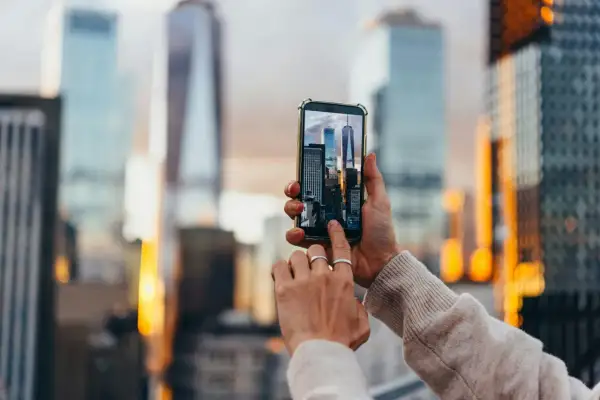 En person håller upp en mobiltelefon för att skanna bild av skyskrapor i New York.