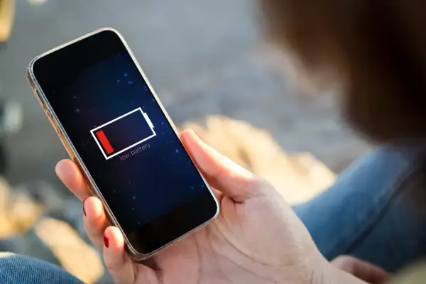 En person håller en mobil med lågt batteri. Dags att uppdatera telefonen och hitta en laddare!